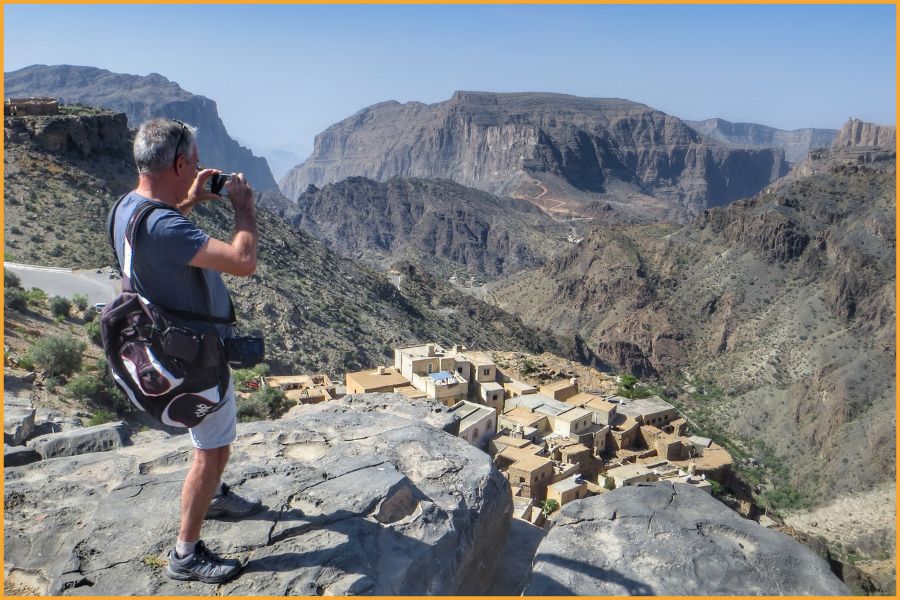 - traveller photographing a traditional mountain village high on Jebel Akhdar in Oman, showcasing the dramatic and safe landscapes of the Arabian Peninsula.
