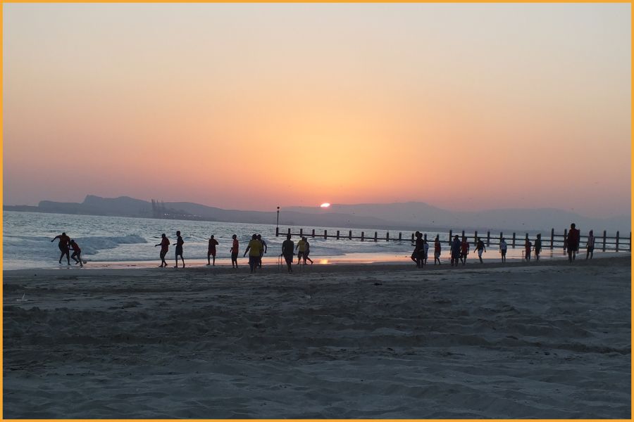 Local men playing barefoot football on an Omani beach at sunset, reflecting the relaxed, friendly and everyday atmosphere travellers experience on the Arabian Peninsula