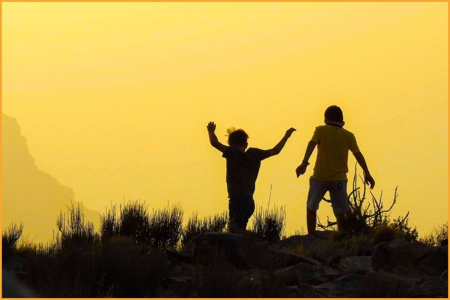 Two young boys playing freely at sunset on Jebel Akhdar in Oman, reflecting the safe, relaxed environment families enjoy in the Arabian Peninsula