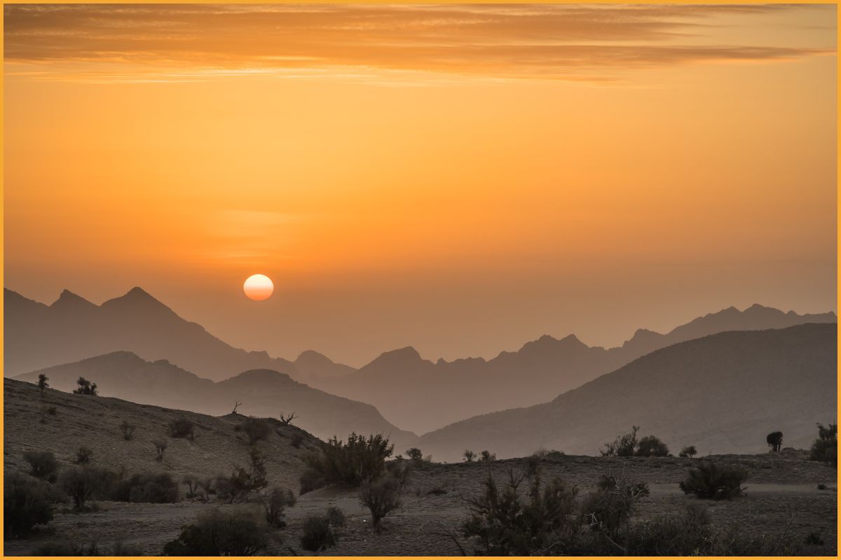Sunset over Jebel Akhdar in Oman, with layered mountain silhouettes and golden sky, reflecting the peaceful, scenic appeal of travel in the Arabian Peninsula.”